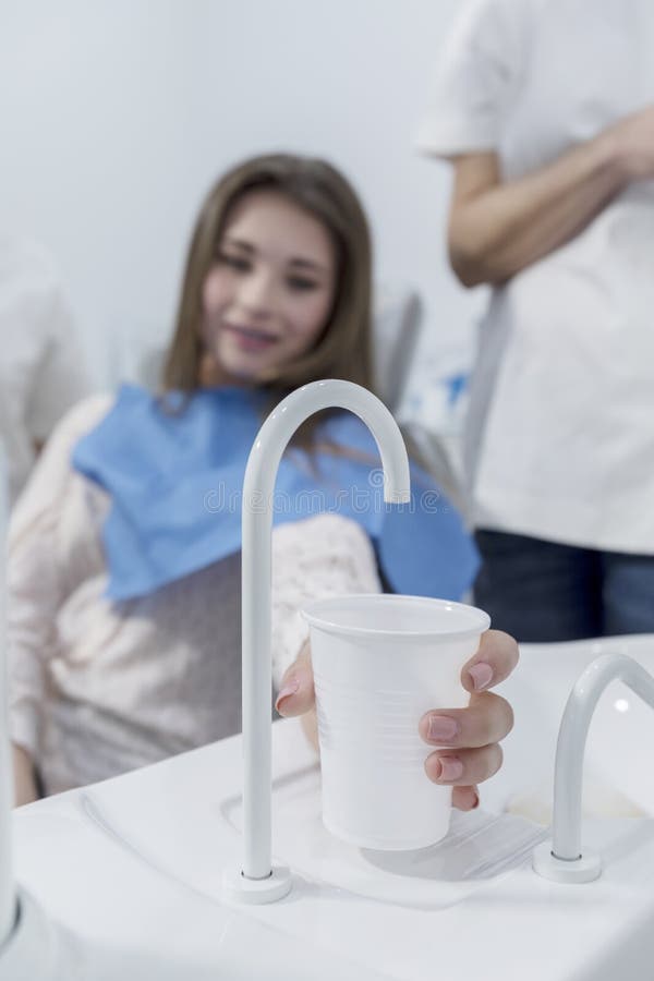Patiënt in tandartsbureau die een kop van water na behandeling nemen royalty-vrije stock foto's Patiënt in tandartsbureau die een kop van water na behandeling nemen royalty-vrije stock foto's