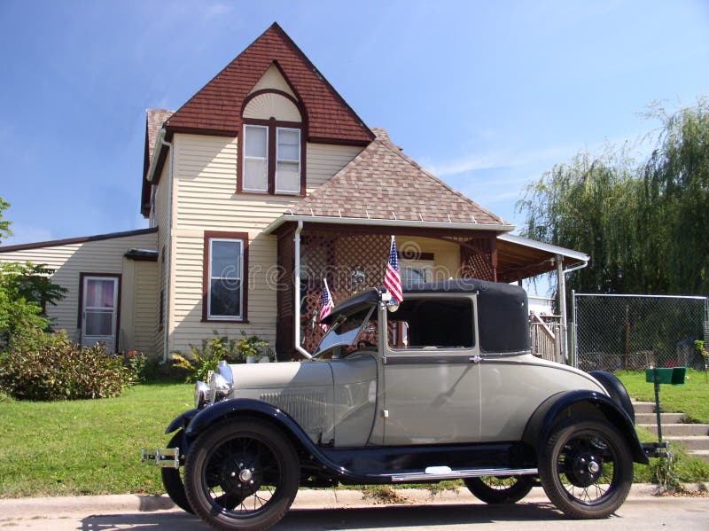 This old car sports patriotic American flags. Parked in front of a vintage house it makes one see that they had nice things in olden times. This old car sports patriotic American flags. Parked in front of a vintage house it makes one see that they had nice things in olden times.