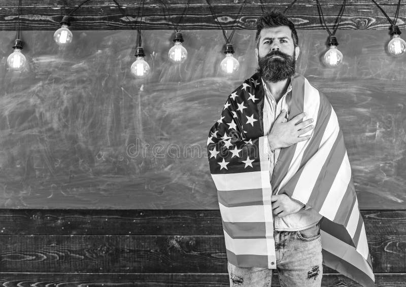 Patriotic education concept. American teacher covered with american flag. Man with beard and mustache on serious face