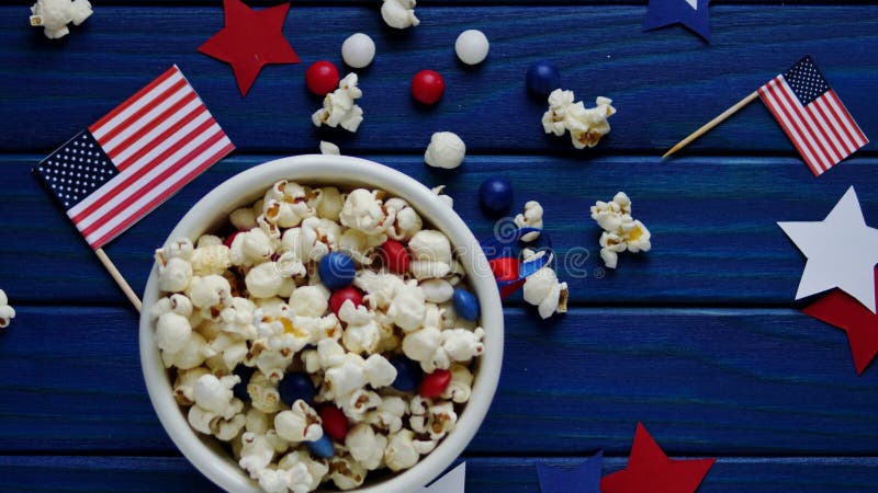 Patriottische popcorn op 4 Juli in een witte emmer met de Amerikaanse vlag op een blauwe houten achtergrond De de onafhankelijkhe stock afbeeldingen Patriottische popcorn op 4 Juli in een witte emmer met de Amerikaanse vlag op een blauwe houten achtergrond De de onafhankelijkhe stock afbeeldingen