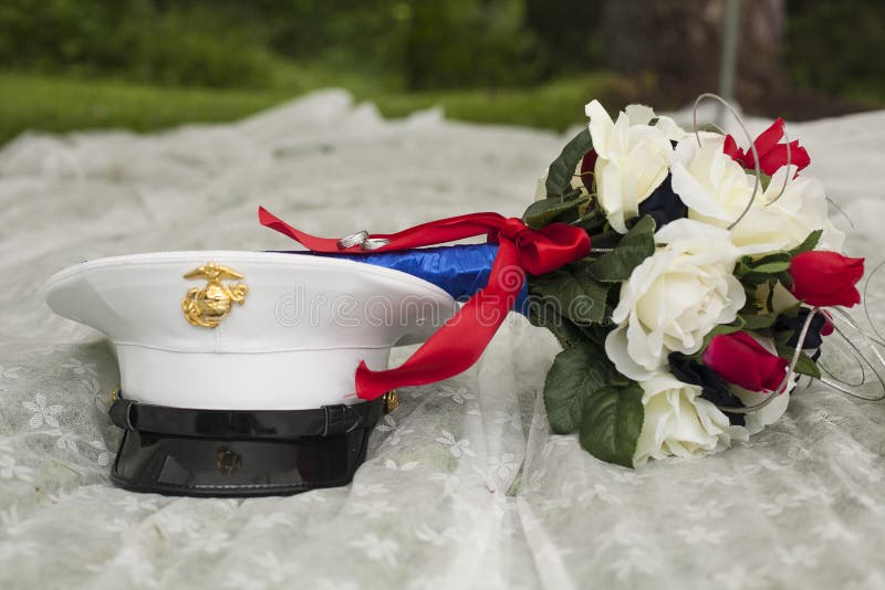 Closeup of patriotic wedding bouquet and military hat on white fabric on grass. Closeup of patriotic wedding bouquet and military hat on white fabric on grass.