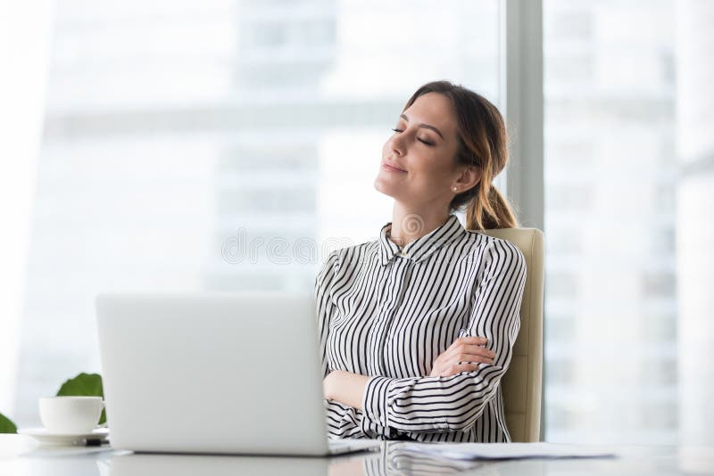 Patron féminin de sourire détendant dans la chaise de bureau avec des yeux fermés photographie stock libre de droits Patron féminin de sourire détendant dans la chaise de bureau avec des yeux fermés photographie stock libre de droits
