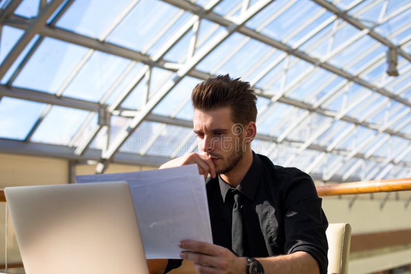 Patrón profesional de sexo masculino confiado que lee los documentos de papel con el contrato fotografía de archivo libre de regalías Patrón profesional de sexo masculino confiado que lee los documentos de papel con el contrato fotografía de archivo libre de regalías