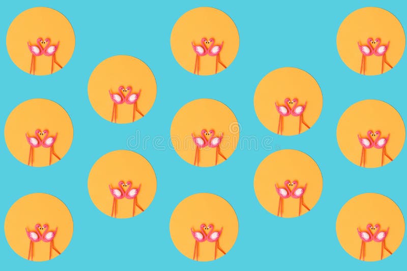 Pattern created of two flamingos toys in orange circle on neon blue background. Top view royalty free stock image