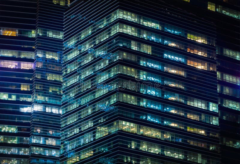 Pattern of office buildings windows illuminated at night. Lighting with Glass architecture facade design with reflection in urban