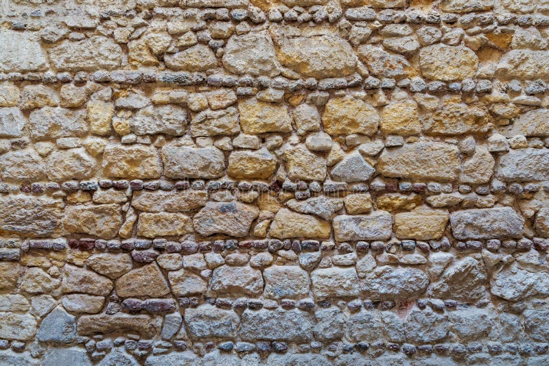 Pattern of yellow and gray decorative grunge weathered uneven stone wall surface