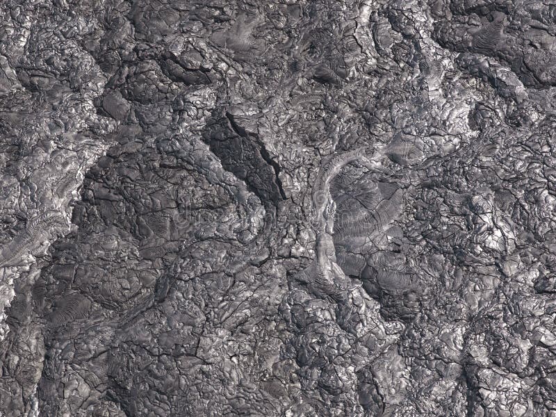 Patterns cracks and shapes emerge from this close up portion of black solidified lava