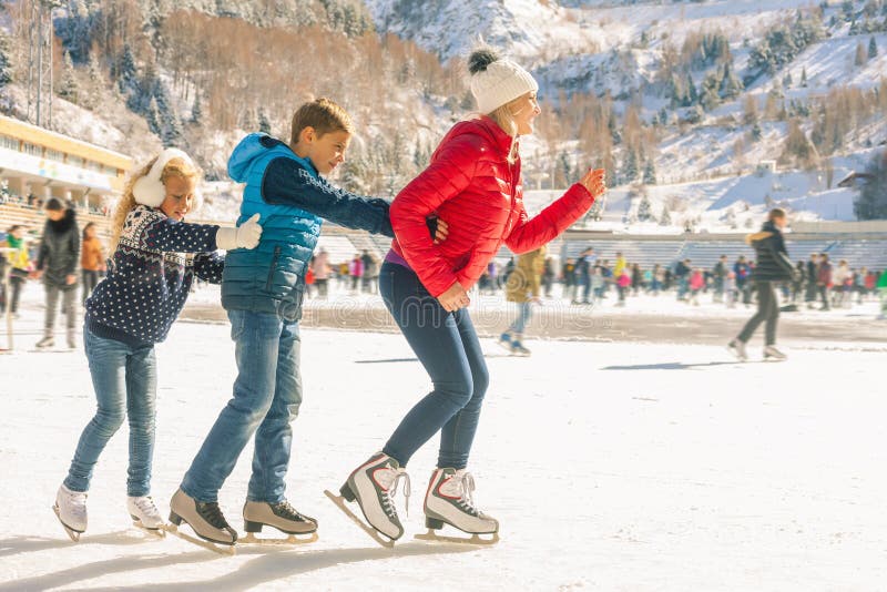 Pattinaggio su ghiaccio all'aperto della famiglia felice alla pista di pattinaggio Attività di inverno