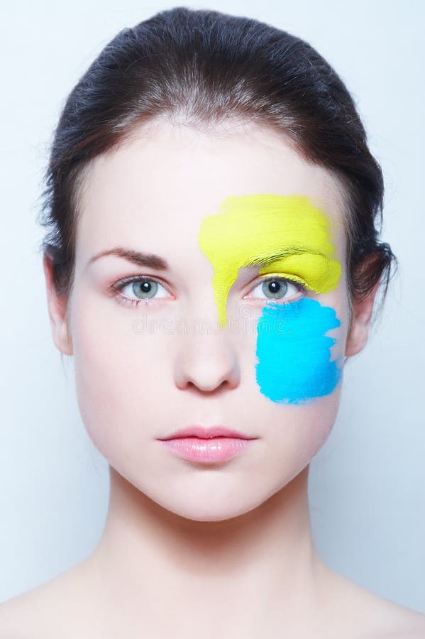 Portrait of a beautiful gentle girl with the original make-up, made with use of a yellow and blue paint. Beauty by Elle Nova. Lovely european female stock images, royalty-free photos and pictures