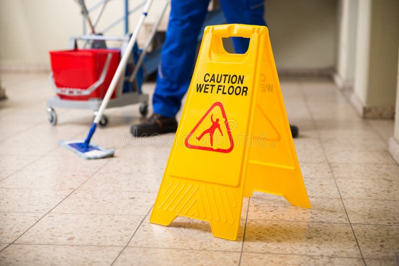 Pavimento passante lo straccio del lavoratore con il segno bagnato di cautela del pavimento