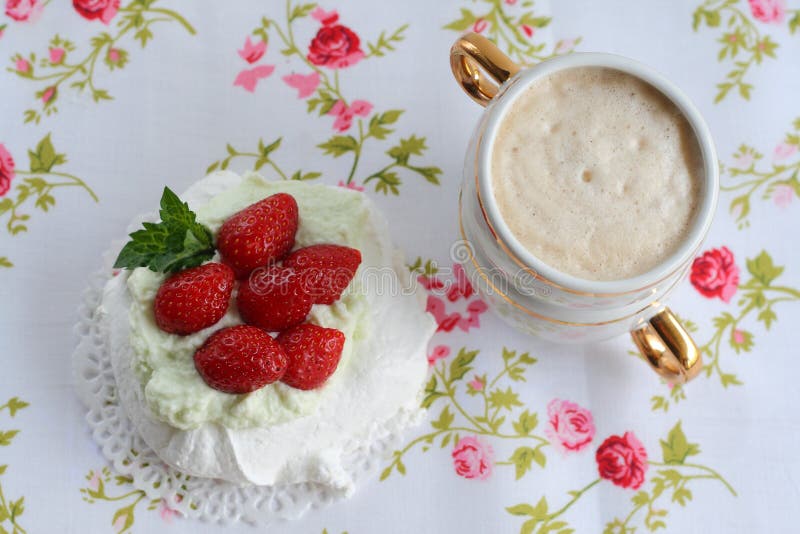 Pavlova kaka med jordgubbar med en kopp av cappuccino på en färgrik servett royaltyfri fotografi Pavlova kaka med jordgubbar med en kopp av cappuccino på en färgrik servett royaltyfri fotografi