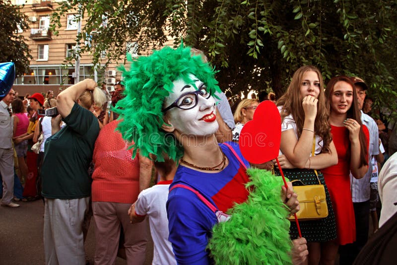 Payaso de sexo femenino en peluca verde y con el corazón en un palillo en el desfile del ` de la cabalgata del circo del ` de los fotos de archivo libres de regalías Payaso de sexo femenino en peluca verde y con el corazón en un palillo en el desfile del ` de la cabalgata del circo del ` de los fotos de archivo libres de regalías