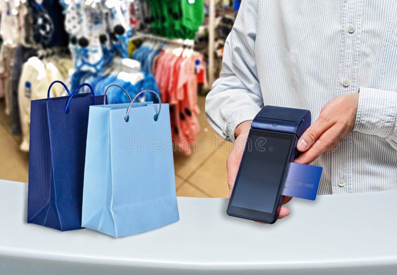 Payment by card purchase in a women`s clothing store. Modern payment blue terminal and card.