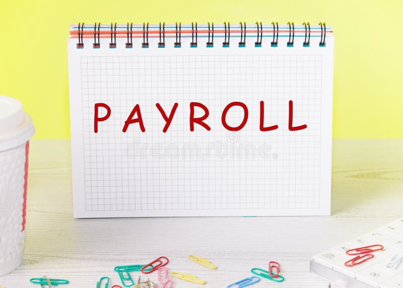 PAYROLL word on a checkered notebook on a yellow background stock photo