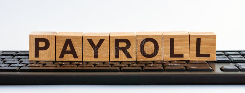 PAYROLL word made with building blocks. A row of wooden cubes with a word written in black font is located on a black keyboard royalty free stock image