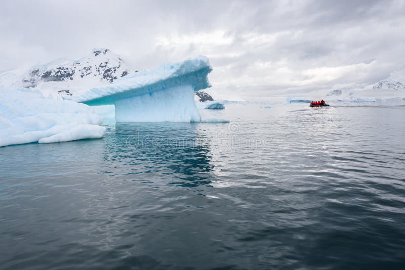 Paysage antarctique dramatique dans le port de Paradise, Antarctique, avec des icebergs sculpturaux et petit un radeau gonflable image libre de droits Paysage antarctique dramatique dans le port de Paradise, Antarctique, avec des icebergs sculpturaux et petit un radeau gonflable image libre de droits