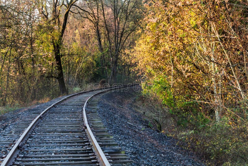 Empty railroad tracks disappear around the bend amid bright fall foliage. Empty railroad tracks disappear around the bend amid bright fall foliage