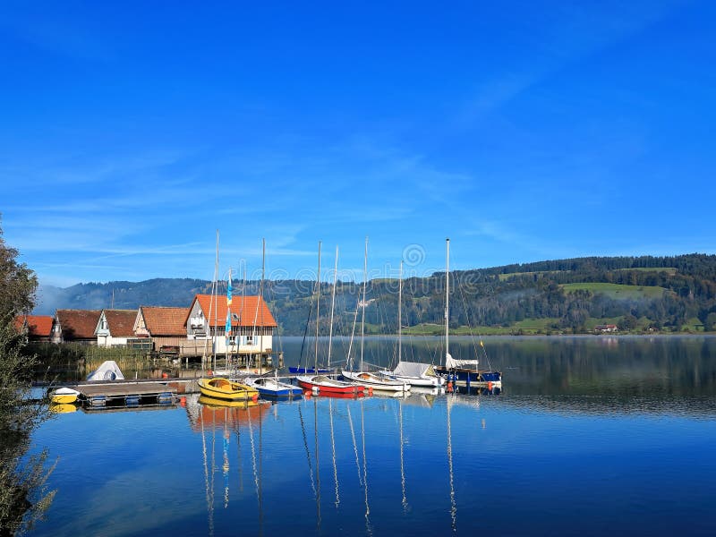 Paysage de lac avec les maisons d'échasse et les bateaux à voile modernes photo stock Paysage de lac avec les maisons d'échasse et les bateaux à voile modernes photo stock
