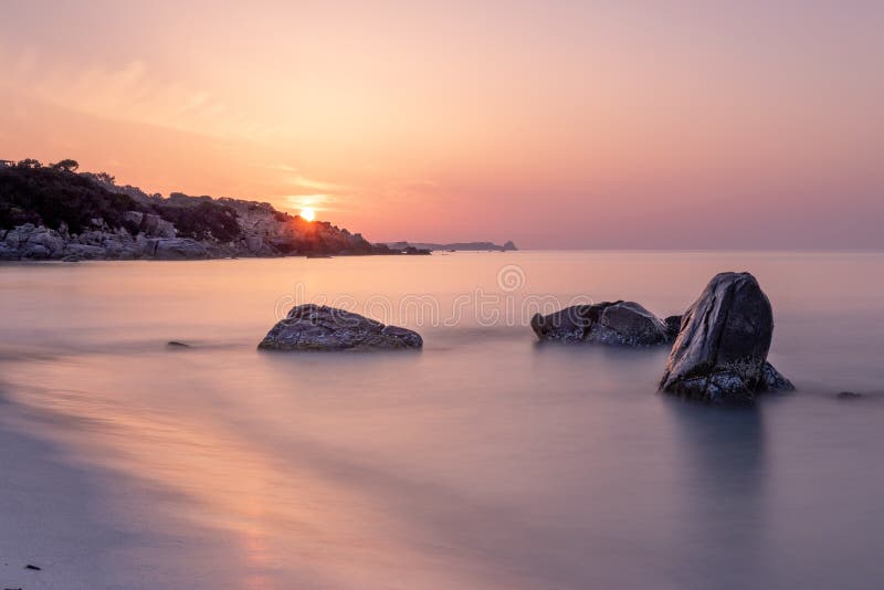 Paysage de lever de soleil avec les vagues de doux et le ciel orange avec Sun, Sardaigne Italie photographie stock Paysage de lever de soleil avec les vagues de doux et le ciel orange avec Sun, Sardaigne Italie photographie stock