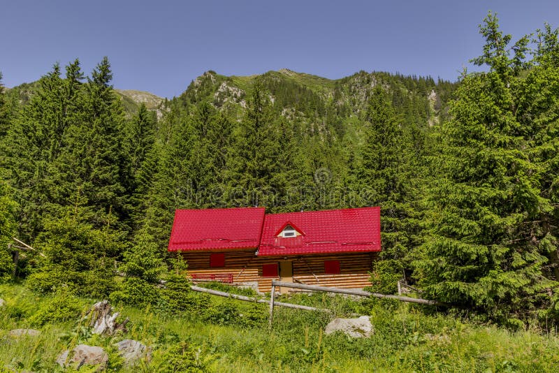 Paysage de montagne avec le chalet en bois de montagne près des avants de pin sous la crête photos libres de droits Paysage de montagne avec le chalet en bois de montagne près des avants de pin sous la crête photos libres de droits