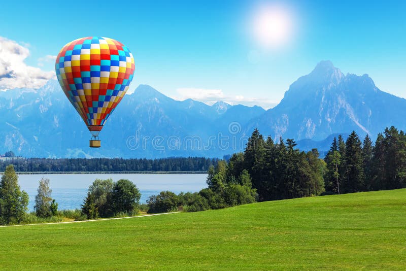 Paysage scénique d'été avec le ballon à air, le lac et les montagnes chaud