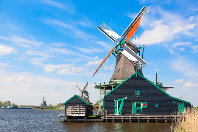 Paysage typique de Néerlandais Vieux moulins à vent néerlandais traditionnels contre le ciel nuageux bleu dans le village de Zaan photo stock Paysage typique de Néerlandais Vieux moulins à vent néerlandais traditionnels contre le ciel nuageux bleu dans le village de Zaan photo stock