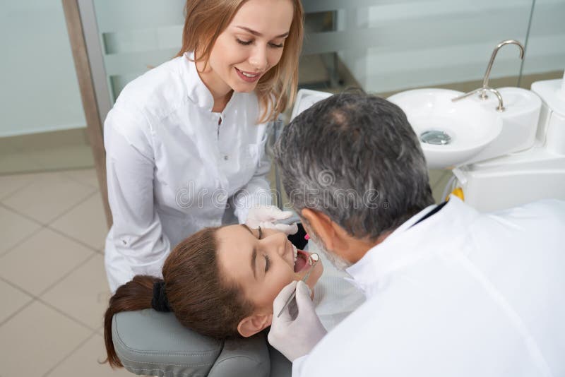 Paziente femminile con la bocca aperta e dentista che controlla i denti fotografie stock Paziente femminile con la bocca aperta e dentista che controlla i denti fotografie stock