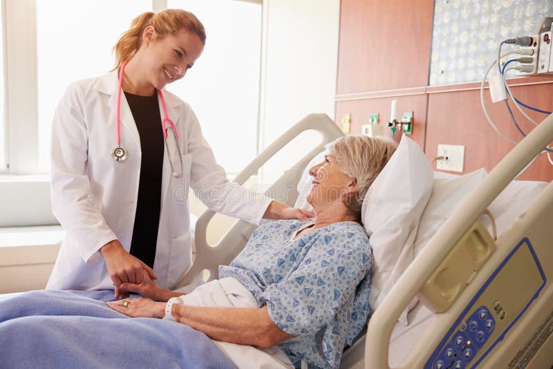 Paziente femminile femminile del dottore Talks To Senior nel letto di ospedale fotografia stock
