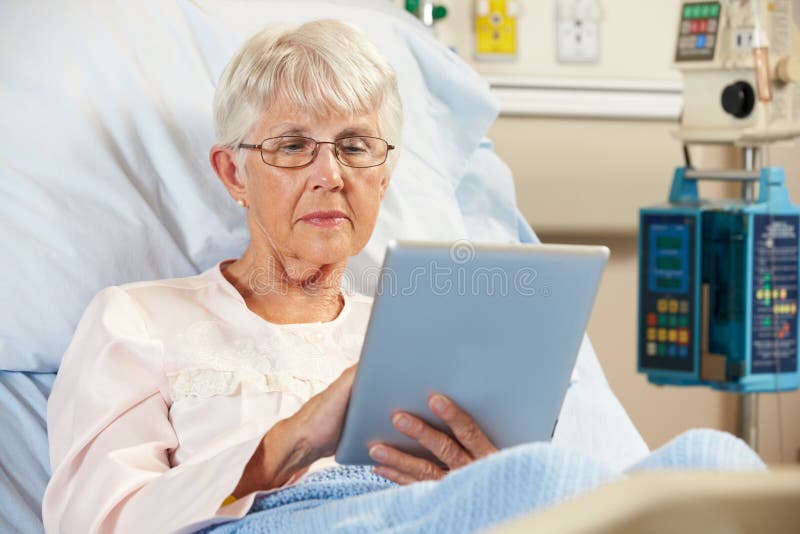 Senior Female Patient Relaxing In Hospital Bed With Digital Tablet. Senior Female Patient Relaxing In Hospital Bed With Digital Tablet