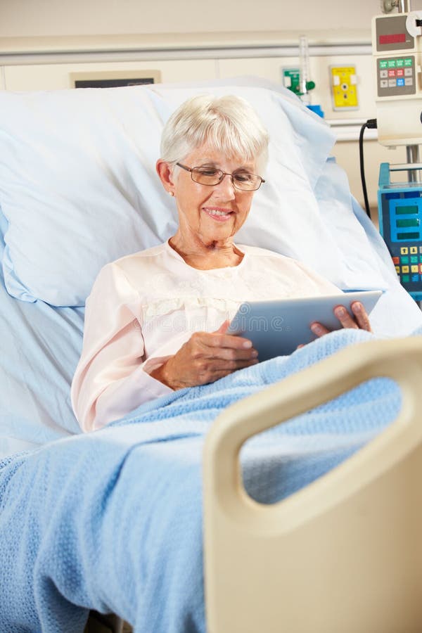 Senior Female Patient Relaxing In Hospital Bed With Digital Tablet Smiling. Senior Female Patient Relaxing In Hospital Bed With Digital Tablet Smiling