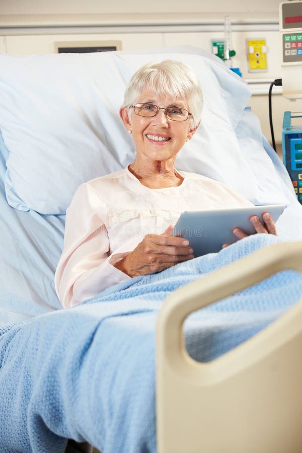 Senior Female Patient Relaxing In Hospital Bed With Digital Tablet Smiling. Senior Female Patient Relaxing In Hospital Bed With Digital Tablet Smiling