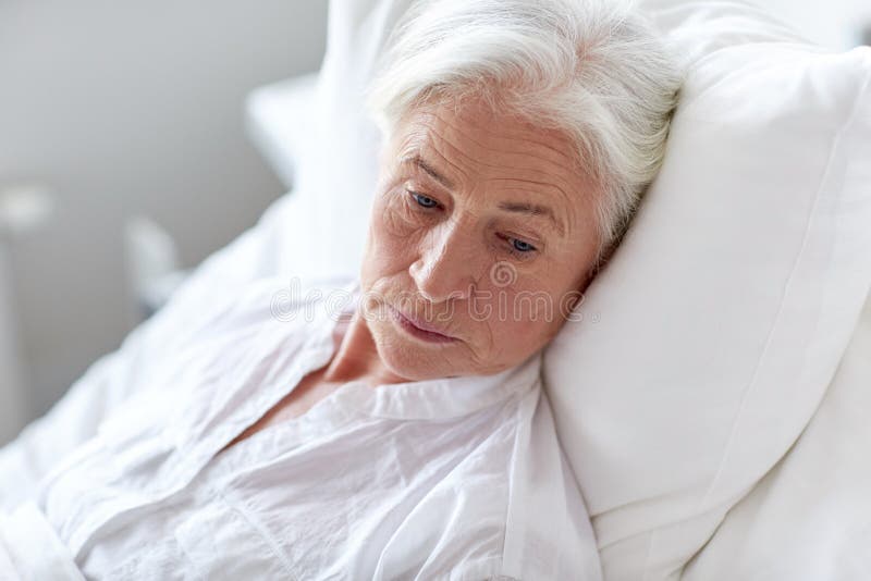 Paziente senior della donna che si trova a letto al reparto di ospedale fotografie stock Paziente senior della donna che si trova a letto al reparto di ospedale fotografie stock
