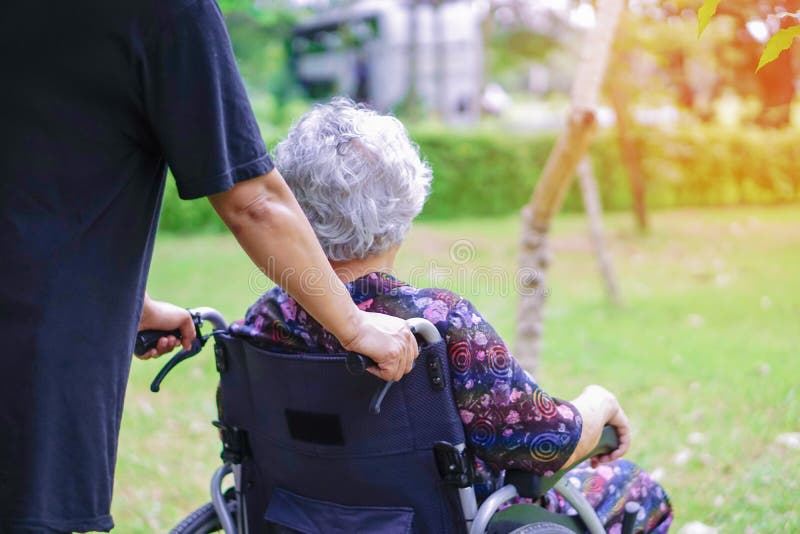 Paziente senior o anziano asiatico della donna della signora anziana con attenzione, aiuto e supporto sulla sedia a rotelle in pa