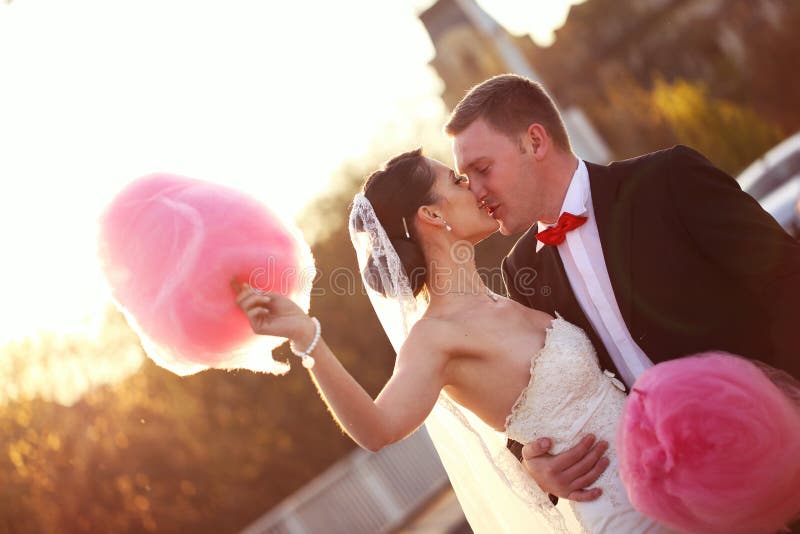 Bride and groom holding a pink cotton candy floss sunny day. Bride and groom holding a pink cotton candy floss sunny day