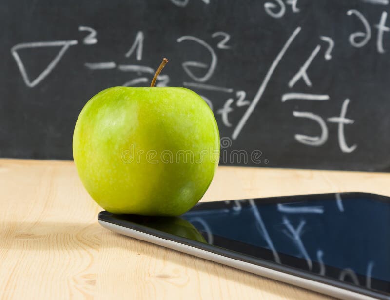 PC de comprimé de Digital et pomme verte devant le tableau noir sur la table en bois photo libre de droits PC de comprimé de Digital et pomme verte devant le tableau noir sur la table en bois photo libre de droits