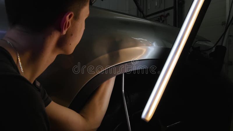 PDR Rimozione di riparazione dell'ammaccatura di Paintless Un tipo giovane pone un'ammaccatura con un gancio d'acciaio senza pitt stock footage PDR Rimozione di riparazione dell'ammaccatura di Paintless Un tipo giovane pone un'ammaccatura con un gancio d'acciaio senza pitt stock footage