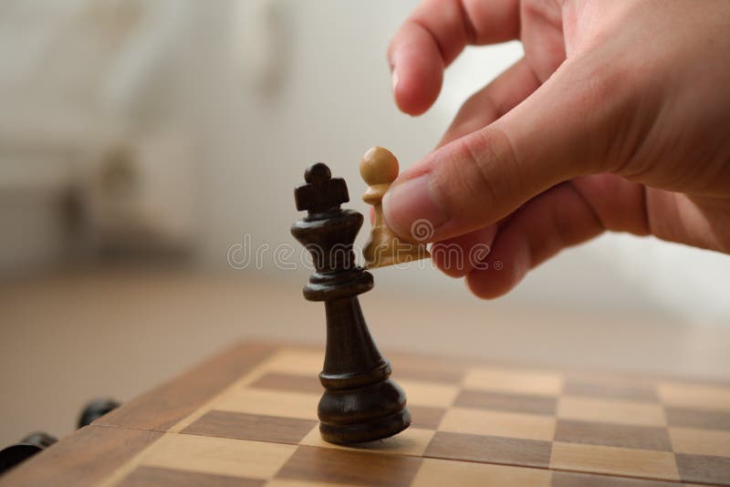 mão segurando uma peça de xadrez, símbolo de xeque-mate do jogo de