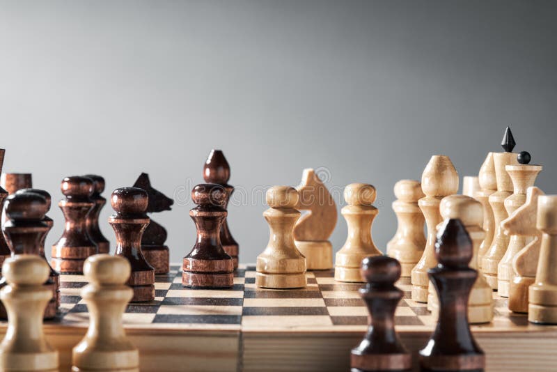 Peças de xadrez de madeira em um tabuleiro de xadrez, o rei branco  encontra-se diante das peças pretas, o conceito de estratégia, planejamento  e tomada de decisão