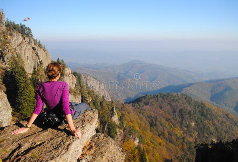 Donna ammirando la vista dal bordo di un dirupo in montagna.