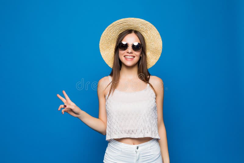 Peace to all Young amazed blogger brunette toothy lady in summer outfit and trendy summer tourist s hat is standing on a light blu stock image Peace to all Young amazed blogger brunette toothy lady in summer outfit and trendy summer tourist s hat is standing on a light blu stock image