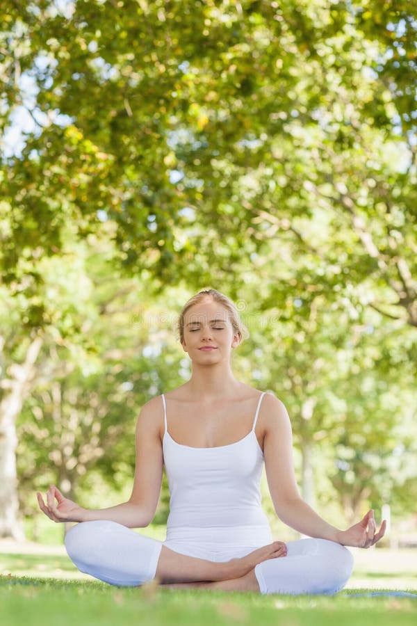 Peaceful attractive woman meditating in a park