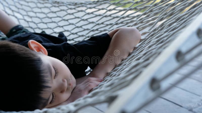 Peaceful Nap: Asian Boy Sleeping Comfortably on a Hammock Outdoors. stock footage