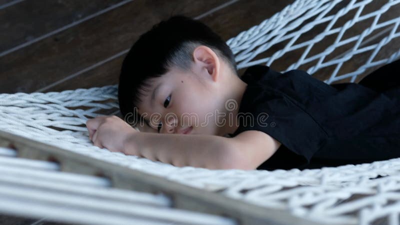 Peaceful Nap: Asian Boy Sleeping Comfortably on a Hammock Outdoors. stock footage