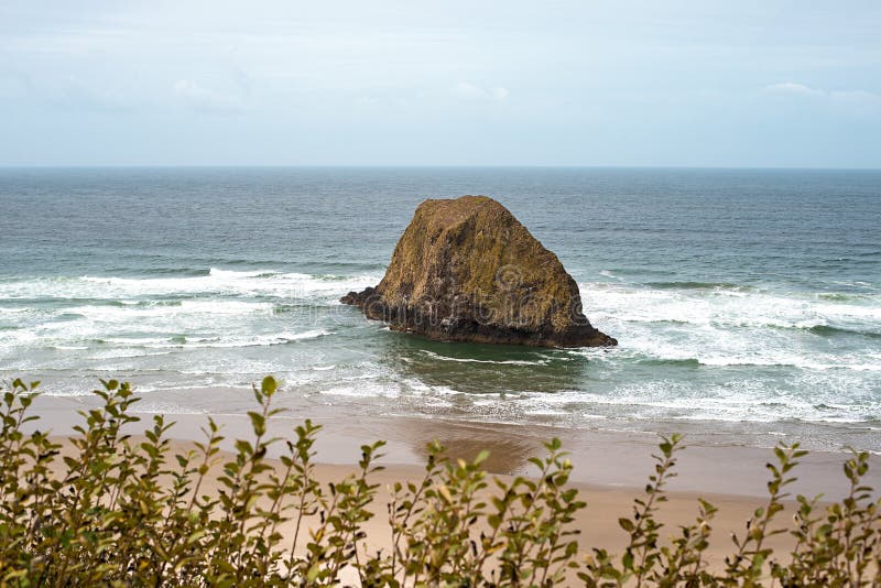 A peaceful Oregon beach coastline with Jockey Cap Rock in the middle, crashing ocean waves. Nature Landscape Background. Island ne