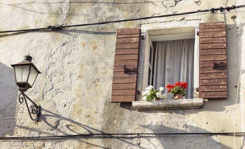 An old building with a charming window with flowers and lamp. Bright red flowers wooden window box charming house stock images, royalty-free photos and pictures