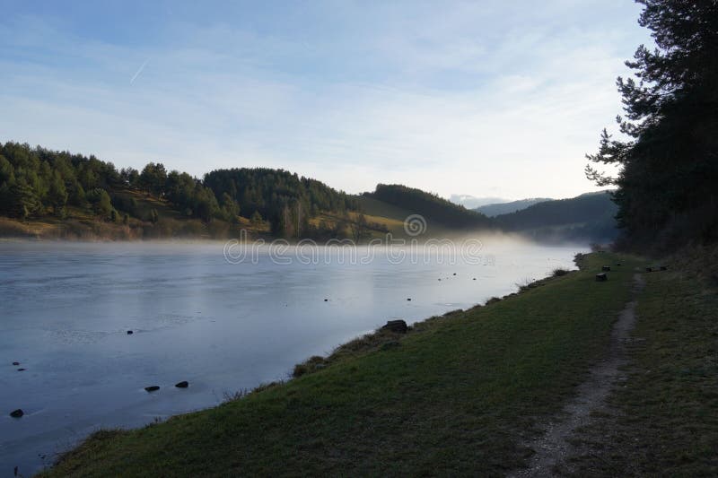 Tichá krajina s hmlou nad zamrznutým jazerom na Slovensku