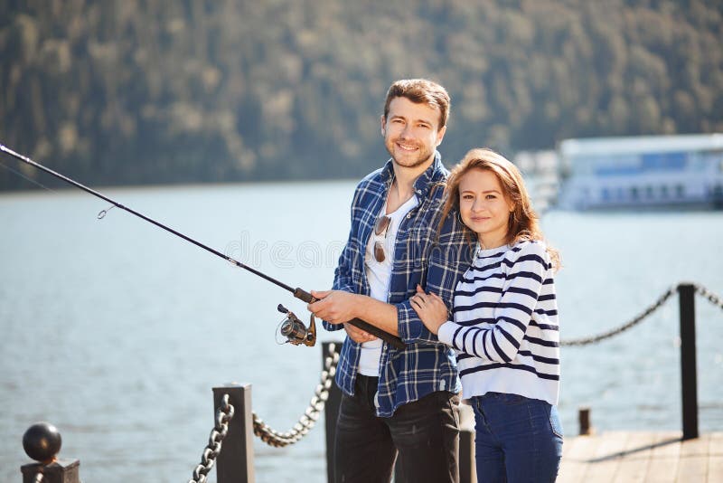 Peaceful young couple fishing with pond in autumn in lake