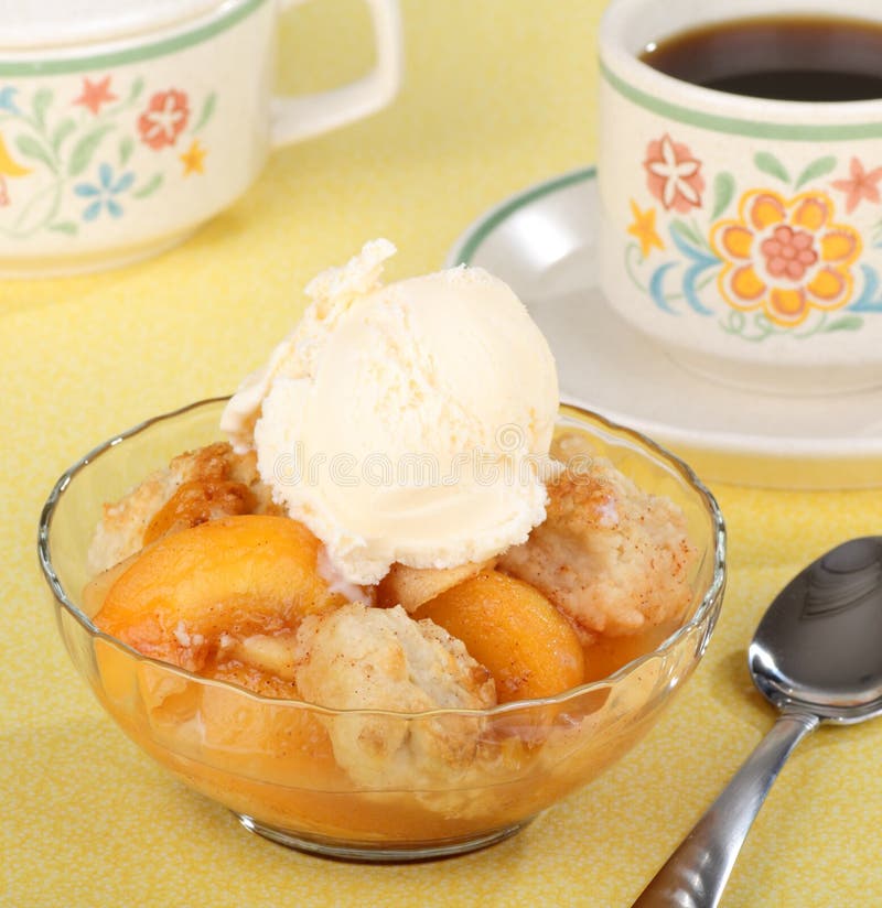 Bowl of peach cobbler with a scoop of ice cream and a cup of coffee. Bowl of peach cobbler with a scoop of ice cream and a cup of coffee