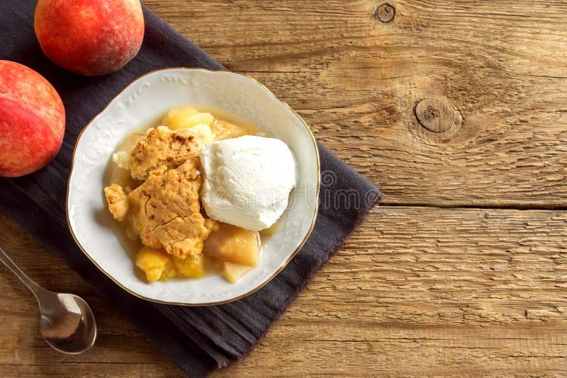 Homemade peach cobbler with vanilla ice cream over rustic wooden background with copy space - healthy pastry dessert. Homemade peach cobbler with vanilla ice cream over rustic wooden background with copy space - healthy pastry dessert