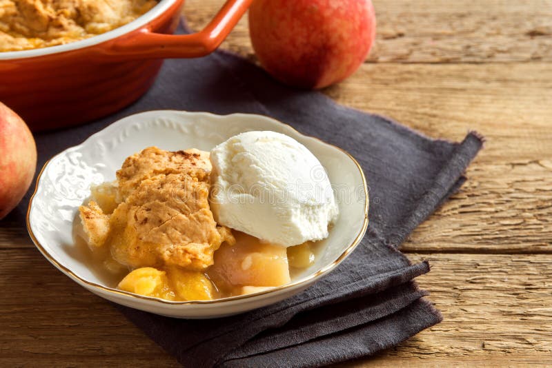 Homemade peach cobbler with vanilla ice cream over rustic wooden background - healthy pastry dessert. Homemade peach cobbler with vanilla ice cream over rustic wooden background - healthy pastry dessert